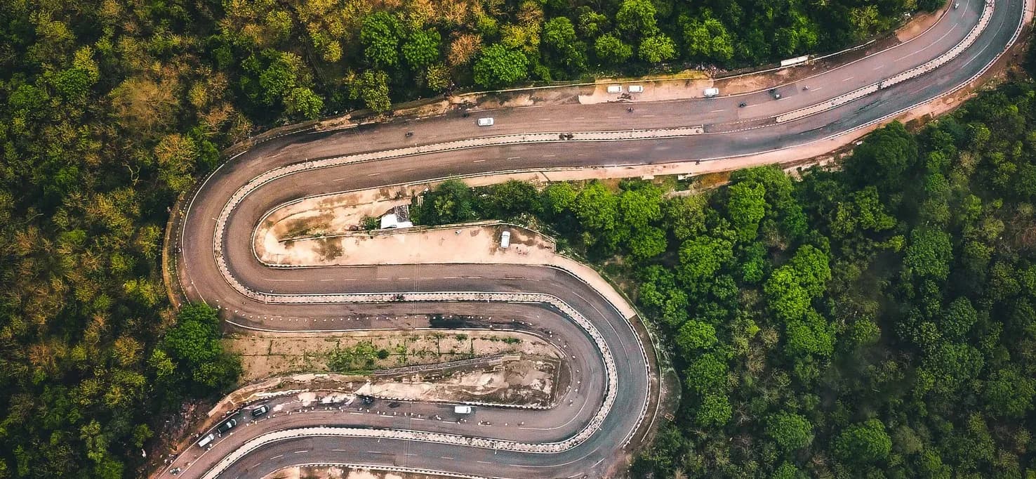 Aerial view of a road winding through dense forest