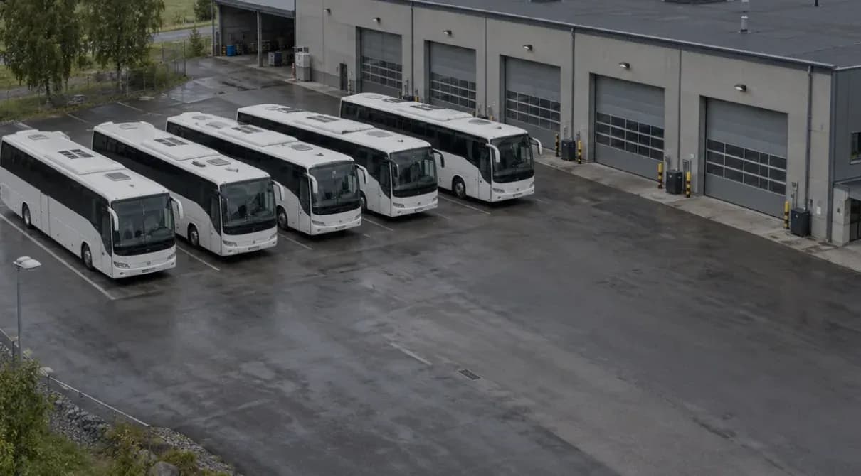 White coaches parked in a row outside a bus depot
