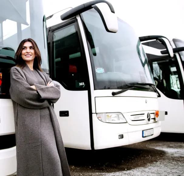 A woman standing in front of a white coach at a depot