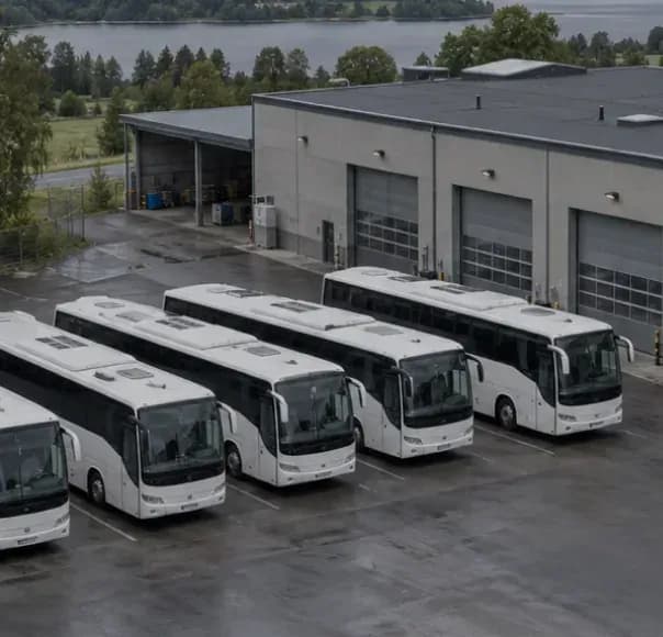 White coaches parked outside a bus depot and workshop